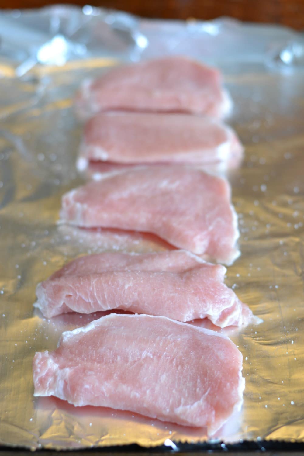 Uncooked pork chops on a baking sheet