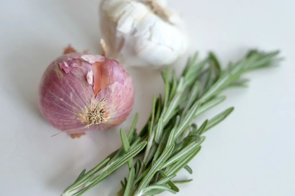 fresh garlic and rosemary on a white cutting board