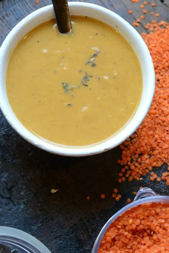 Fresh lentil soup in a white bowl, served in a restaurant setting