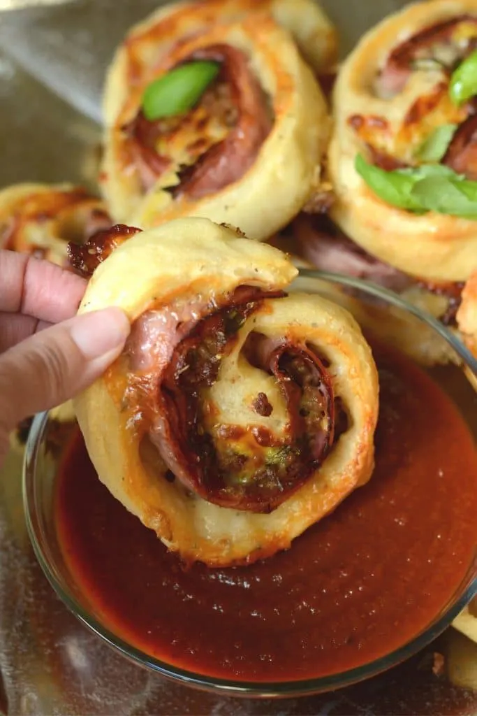 Close up of stromboli roll up dipped in pizza sauce