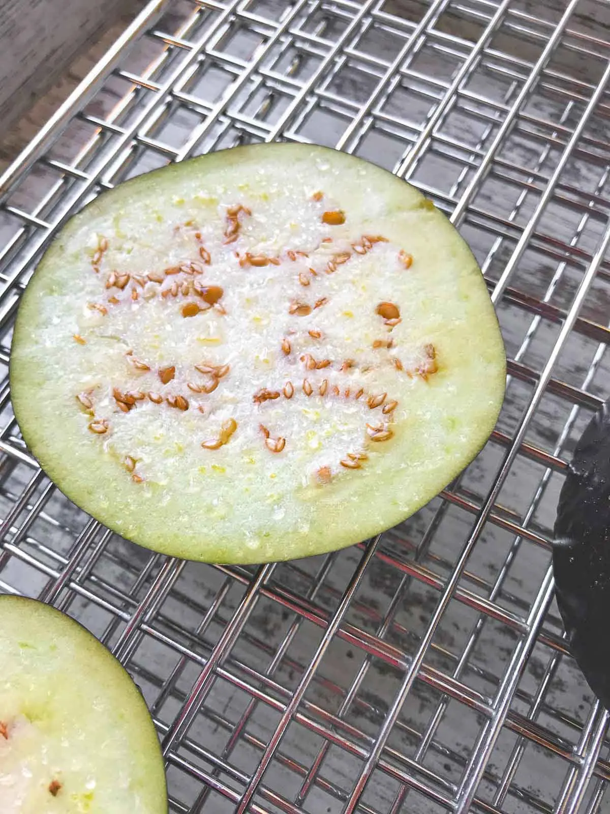 Eggplant with salt on it sweating on a cooking rack.