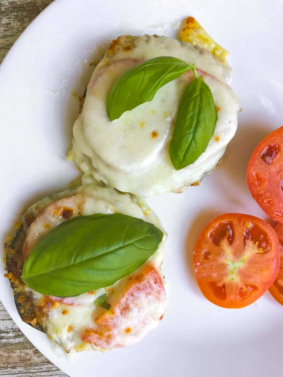 Eggplant Parmesan Rounds on a plate with fresh tomato