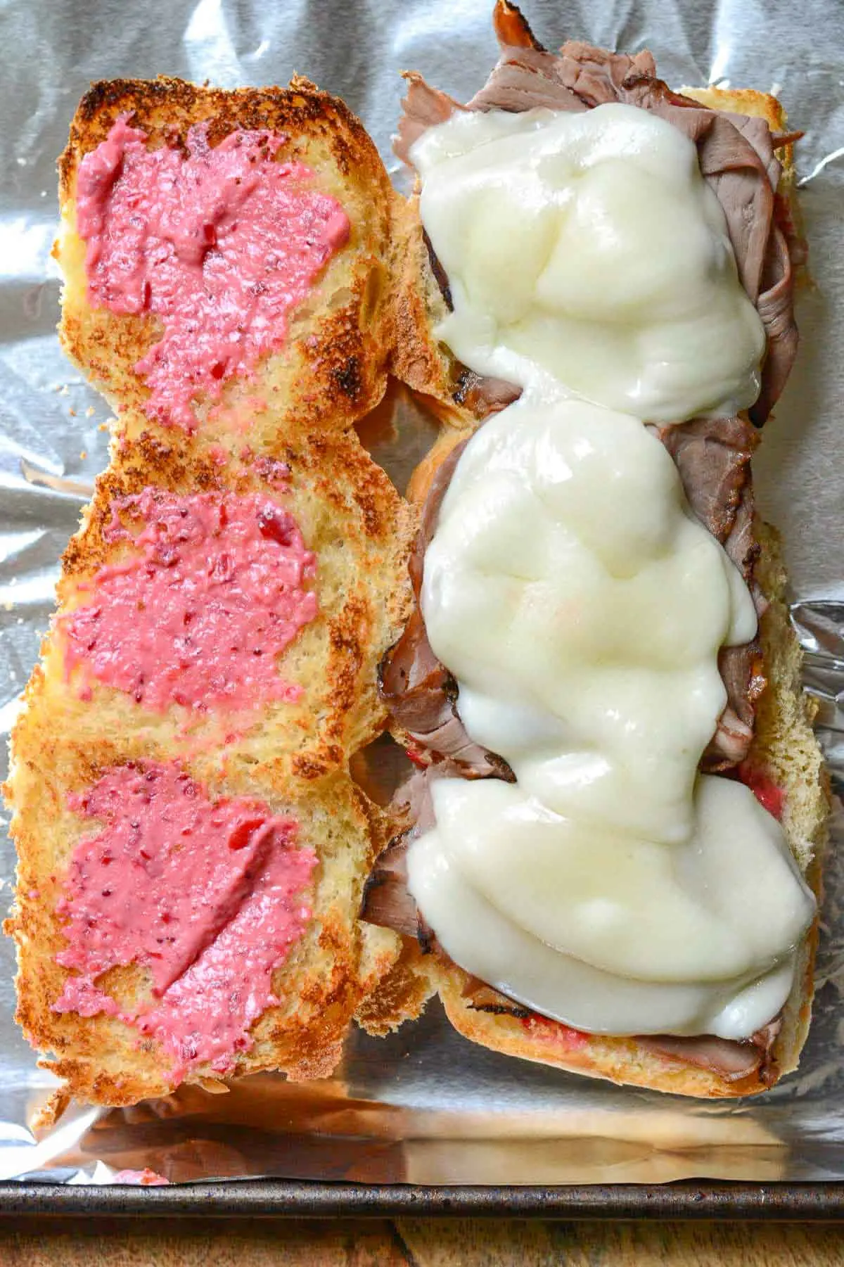 Opened roast beef sliders on a baking sheet