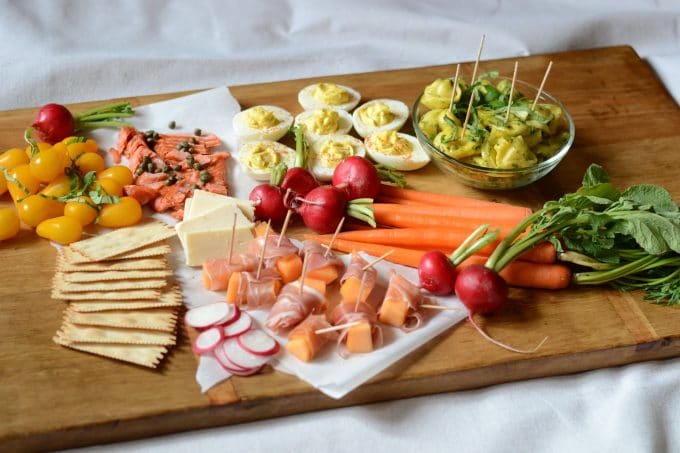 Wooden tray with seasonal vegetables, cheese and appetizers
