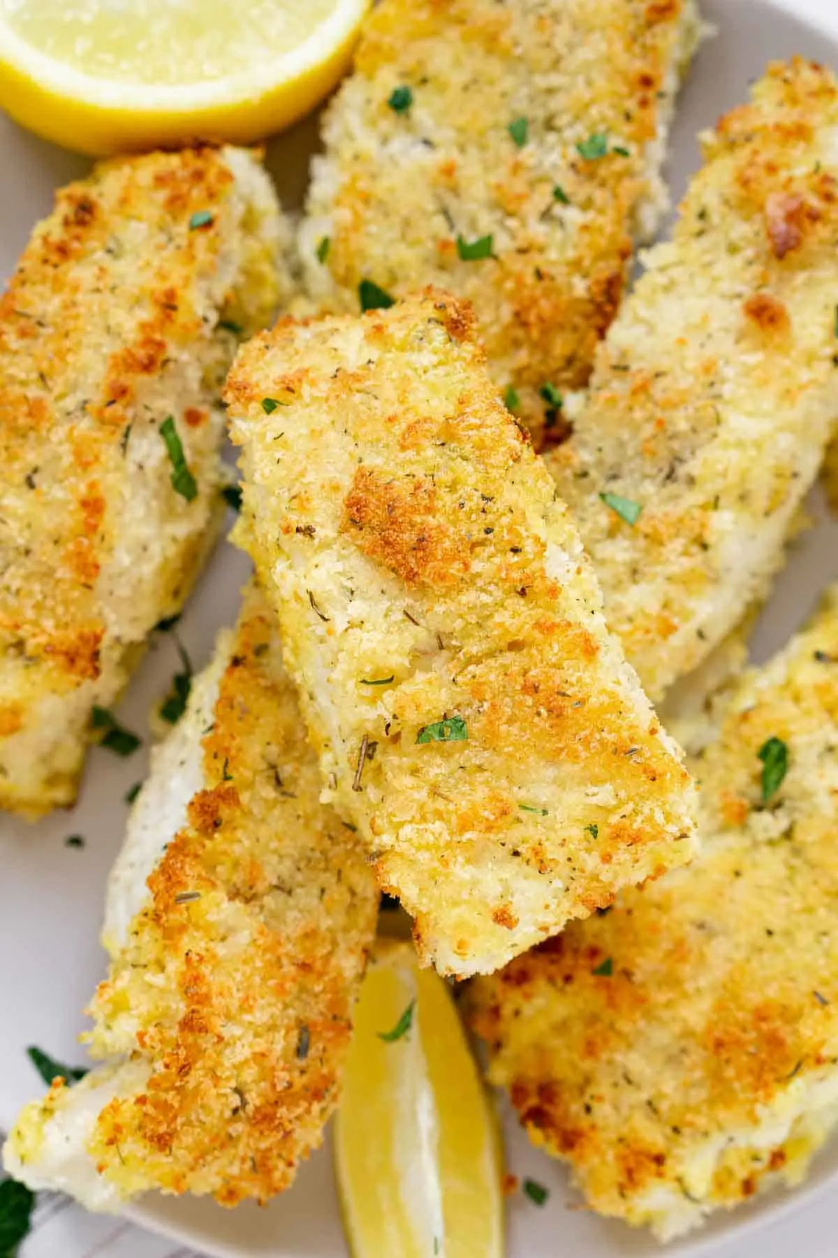 Plate of panko crusted cod fillets garnished with lemon wedegs.