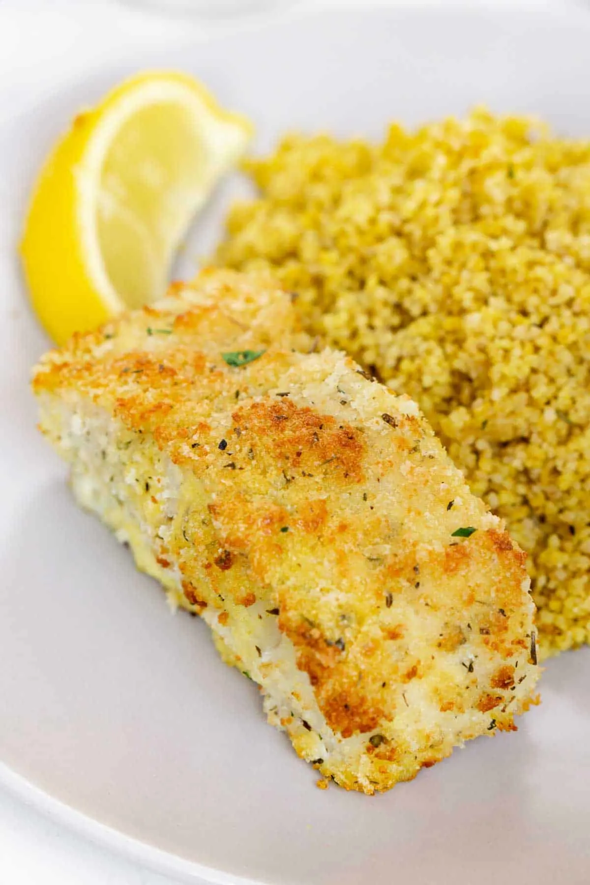 Close up of a panko breaded cod fillet on a plate with couscous.