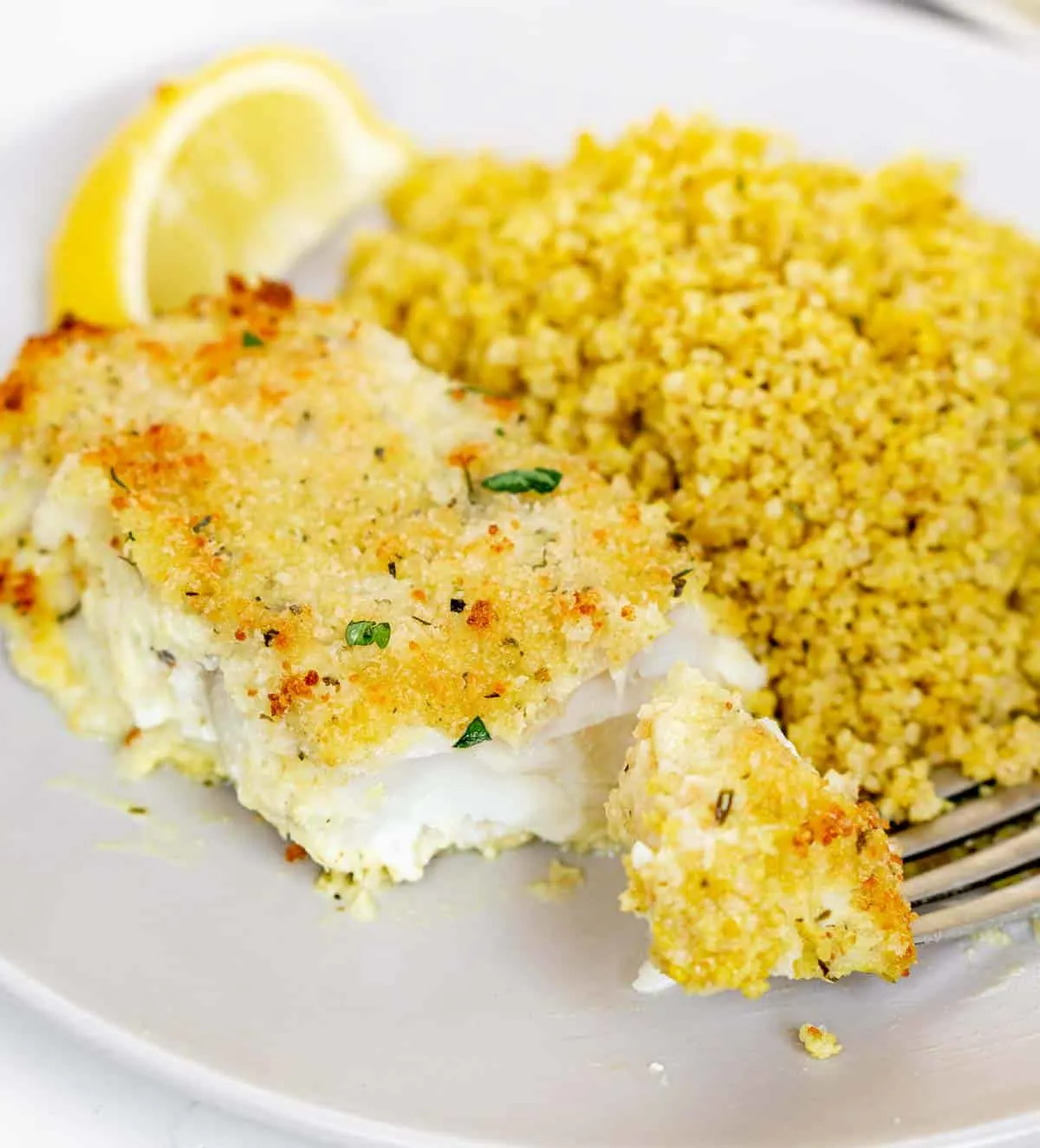 Fork cutting into a panko breaded cod fillet to show texture inside.