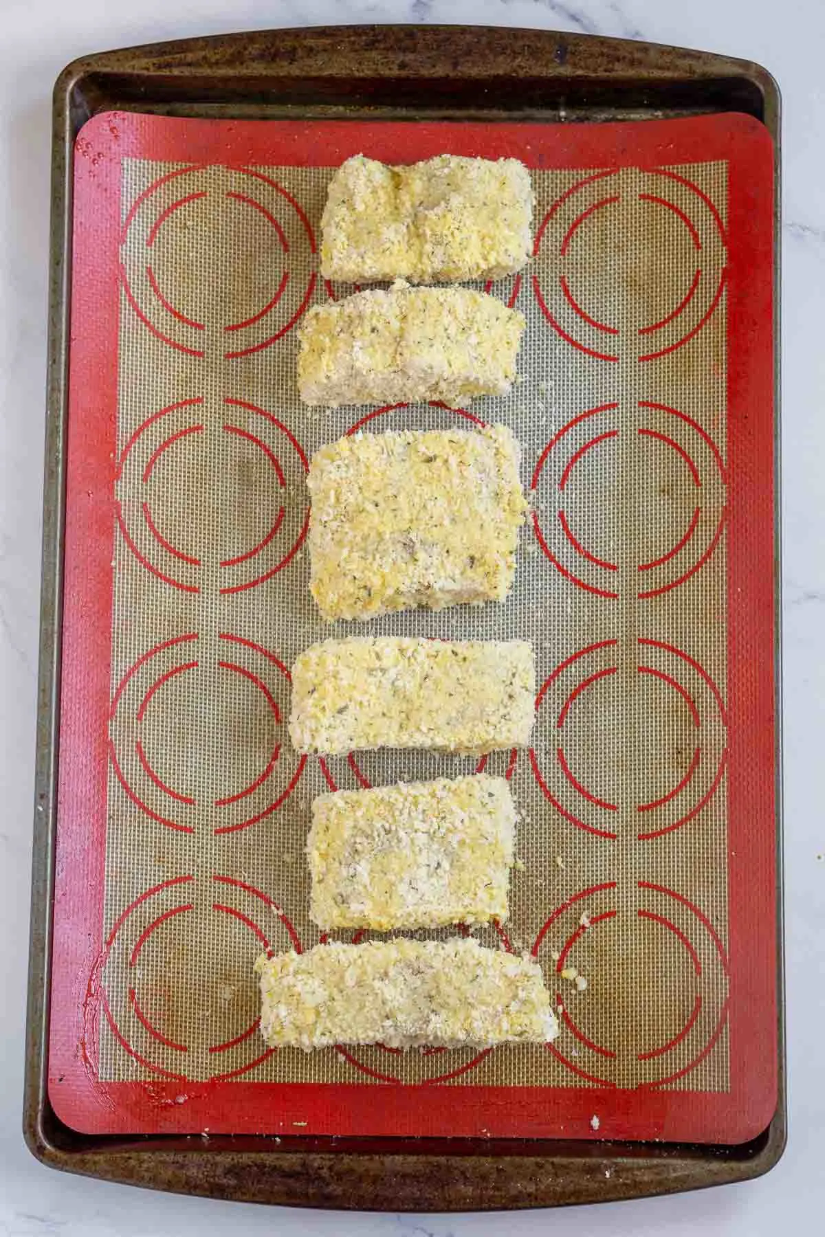 Cod fillets breaded with panko breadcrumbs on a prepared baking sheet.