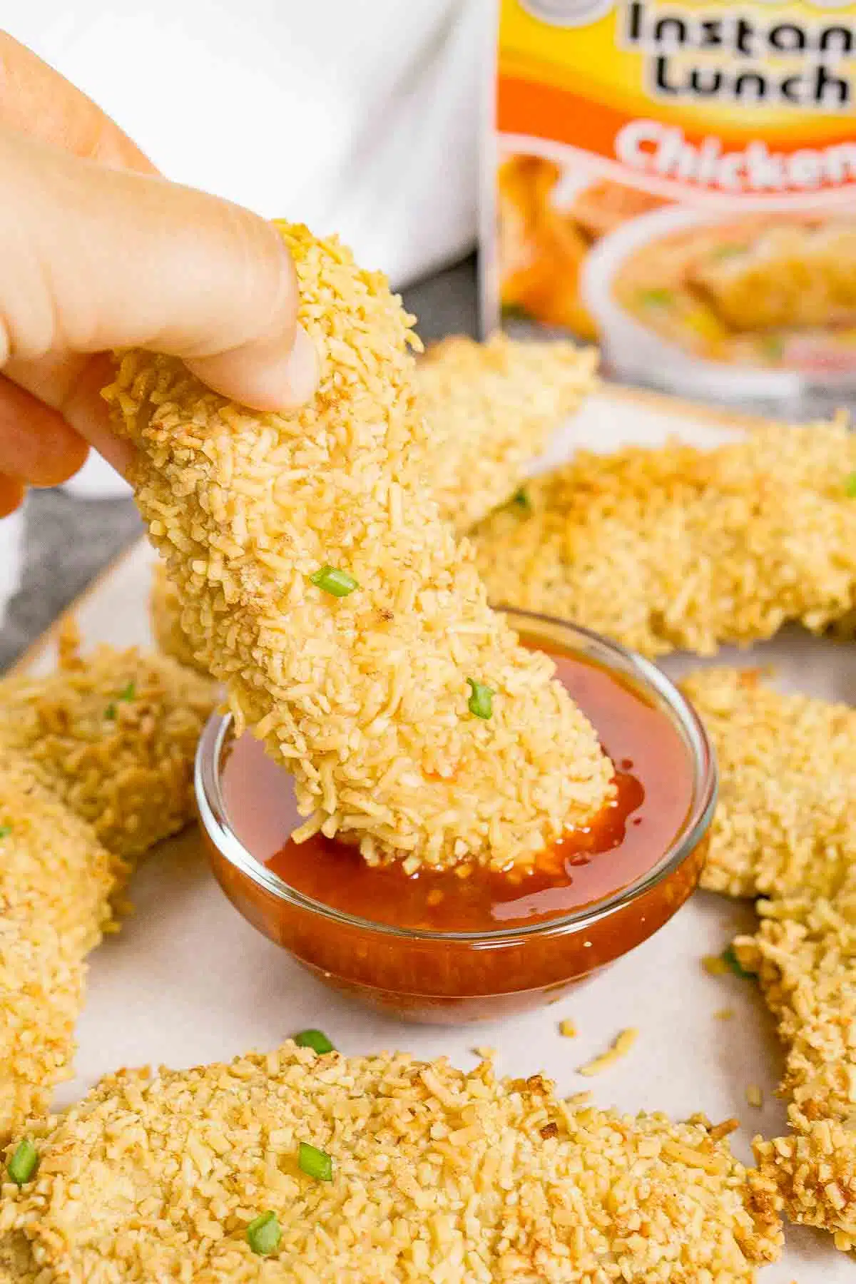 Dipping a baked ramen fried chicken piece into sweet chili sauce