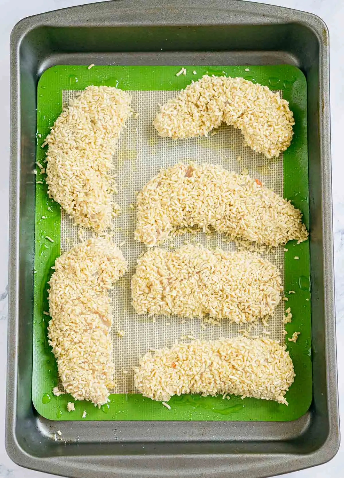 Ramen-coated chicken tenders on a baking sheet
