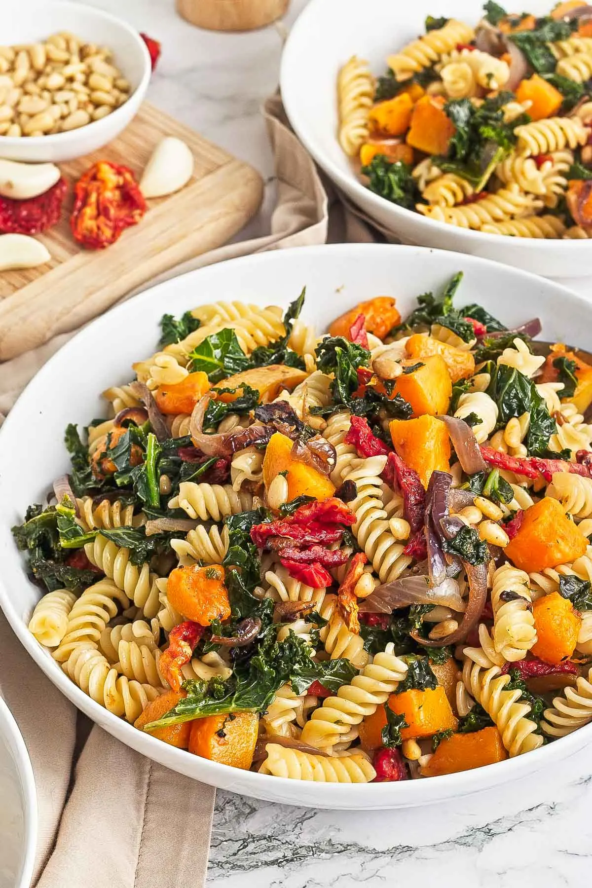 Bowl of butternut kale pasta with sun dried tomato and pine nuts