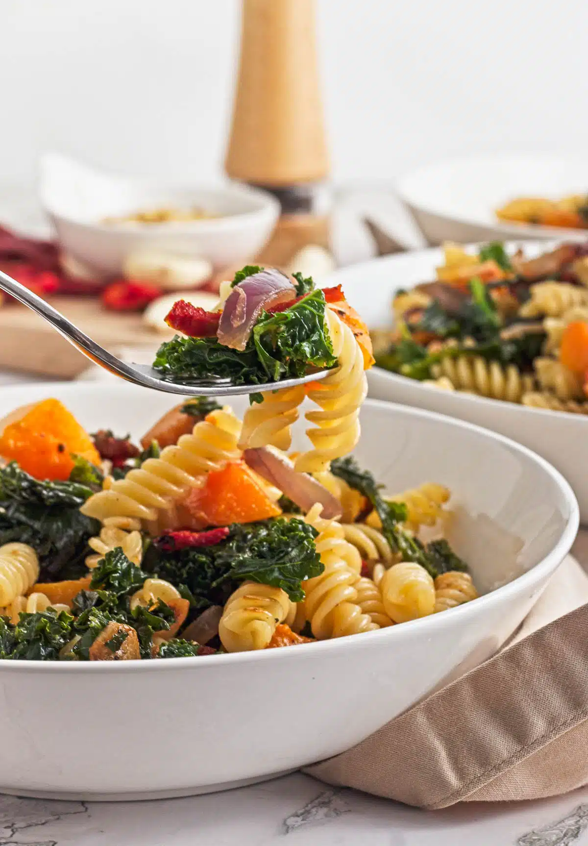 Fork holding butternut squash and kale pasta to show texture