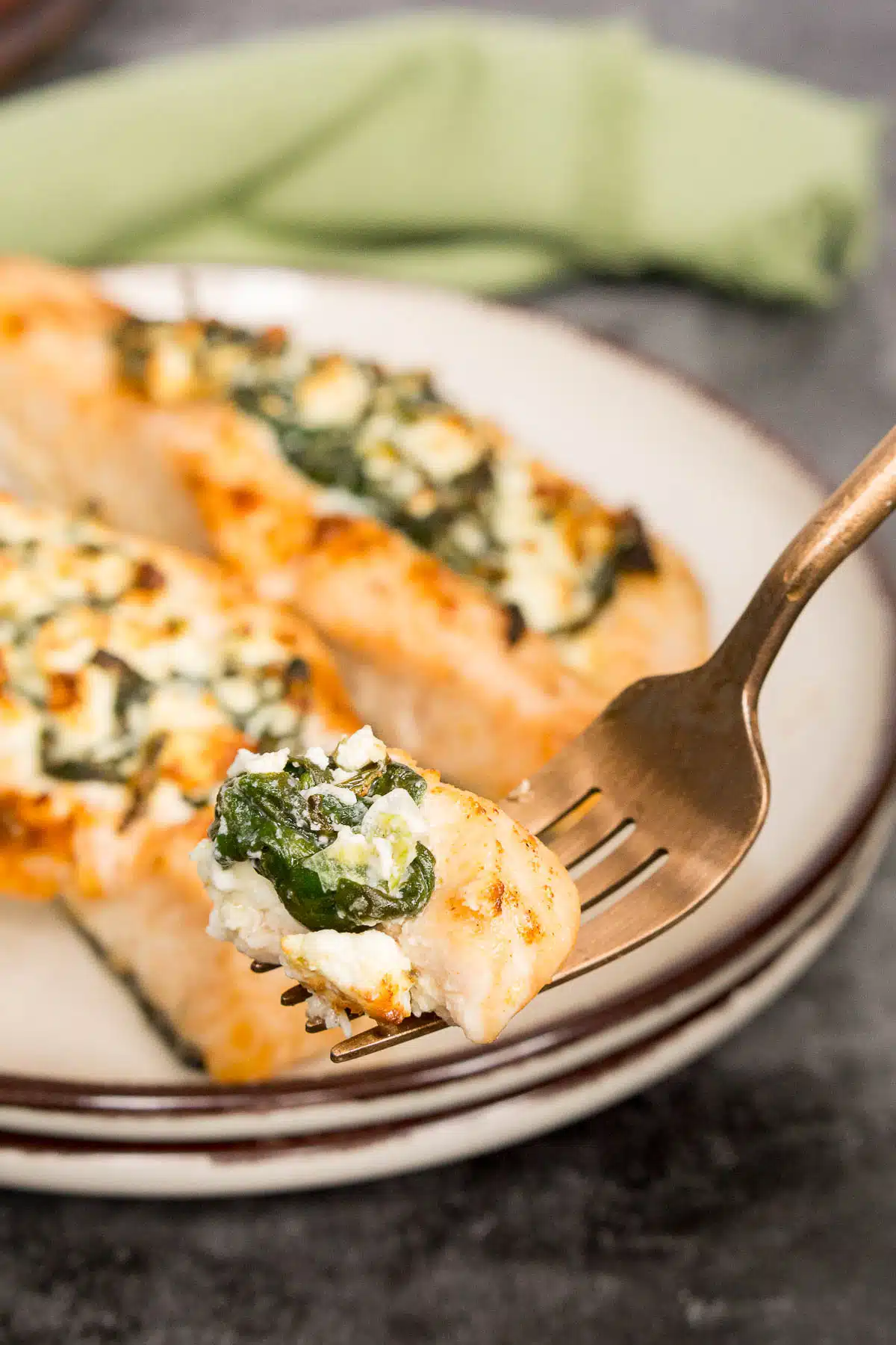 Fork holding piece of salmon with feta and spinach