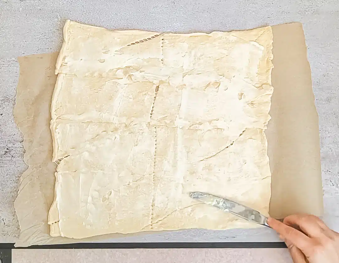 Spreading softened butter over rolled out crescent dough