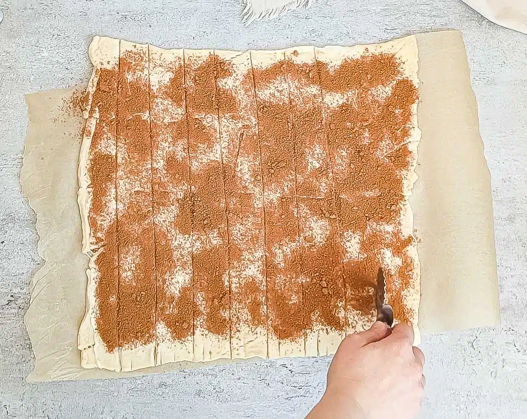 Using a pizza cutter to slice crescent dough for cinnamon rolls