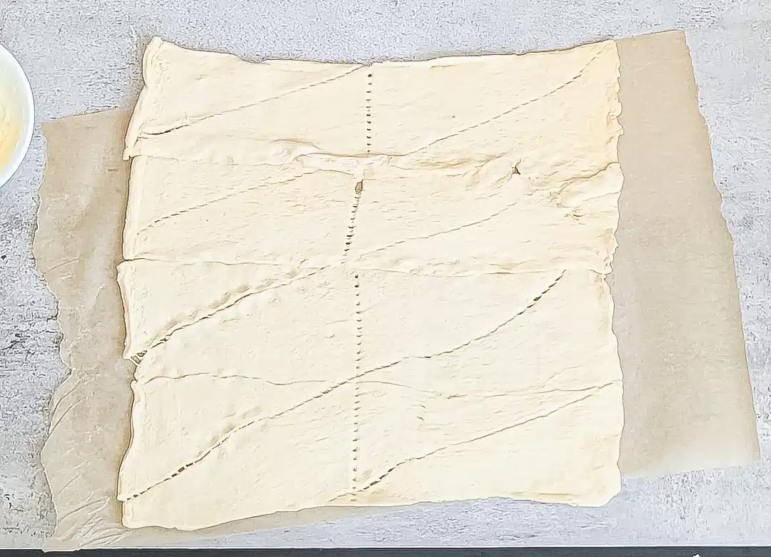 Two tubes of crescent dough laid out and pressed into 1 sheet of dough