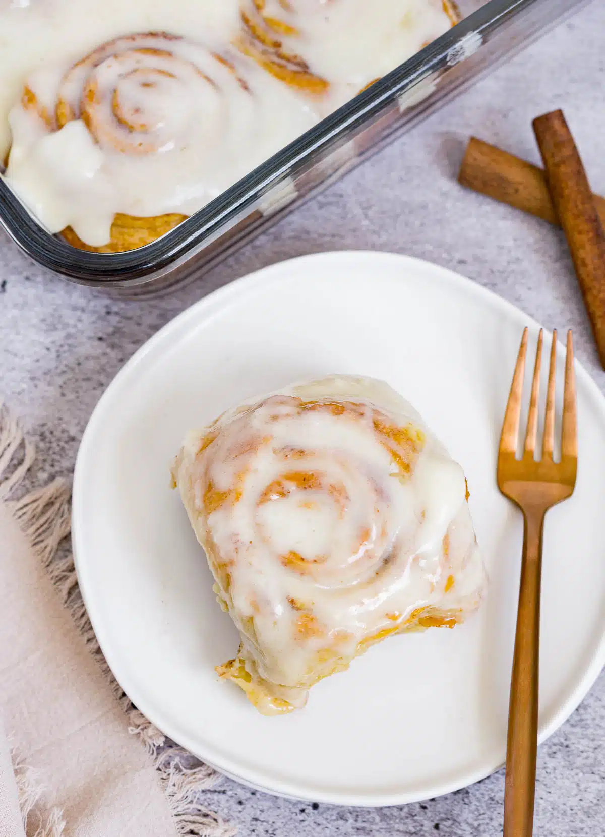 Cinnamon roll with cream cheese icing on a dessert plate
