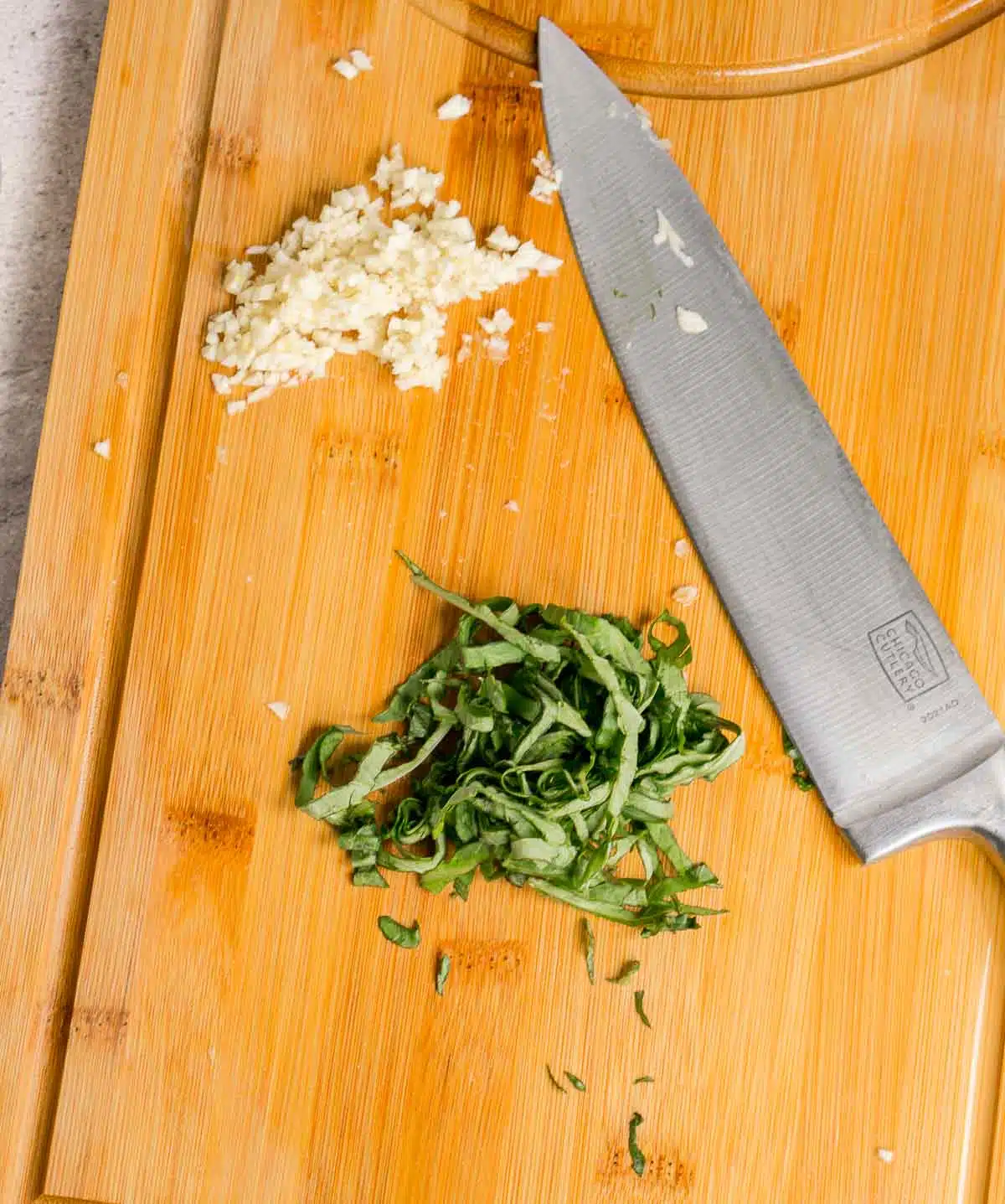 Minced garlic and sliced basil on a cutting board