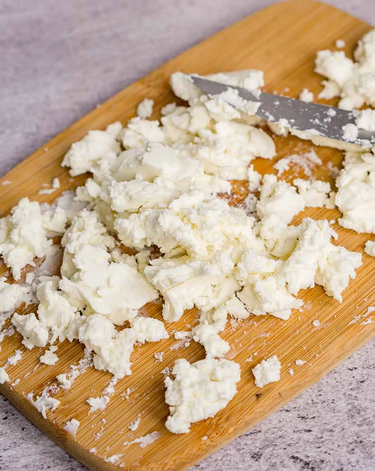 Crumbled goat cheese on a cutting board