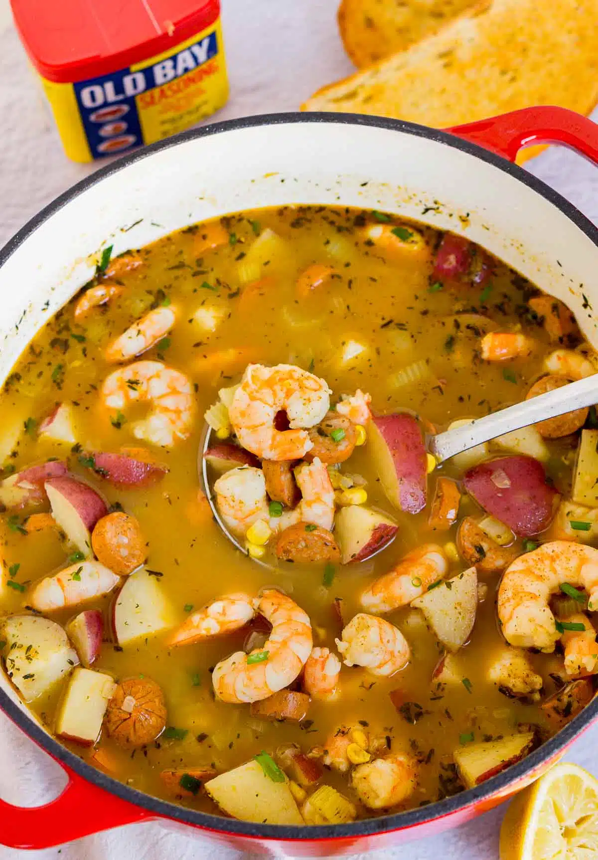 Ladle scooping up shrimp boil soup from a pot