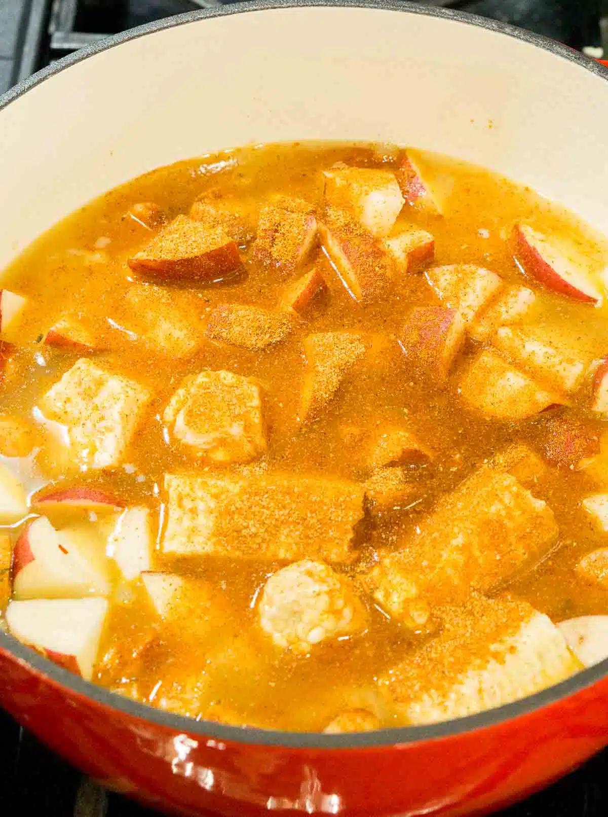 Potatoes, old bay seasoning, and other soup ingredients in a soup pot