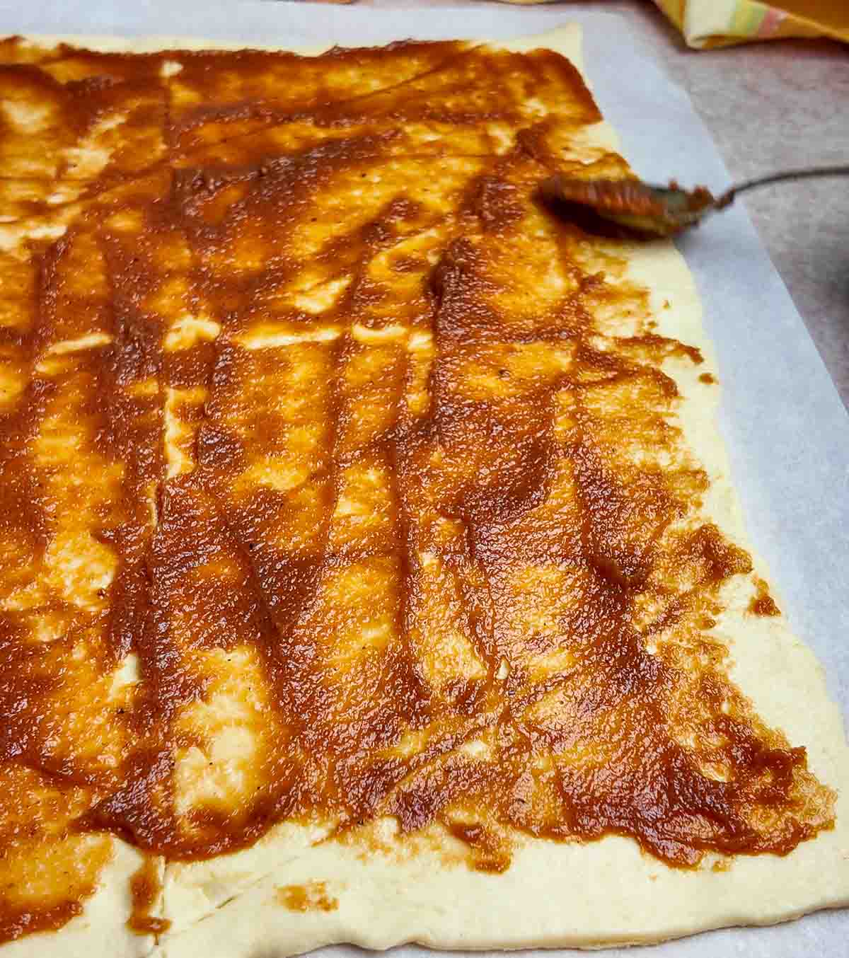 Spreading apple butter on crescent roll dough