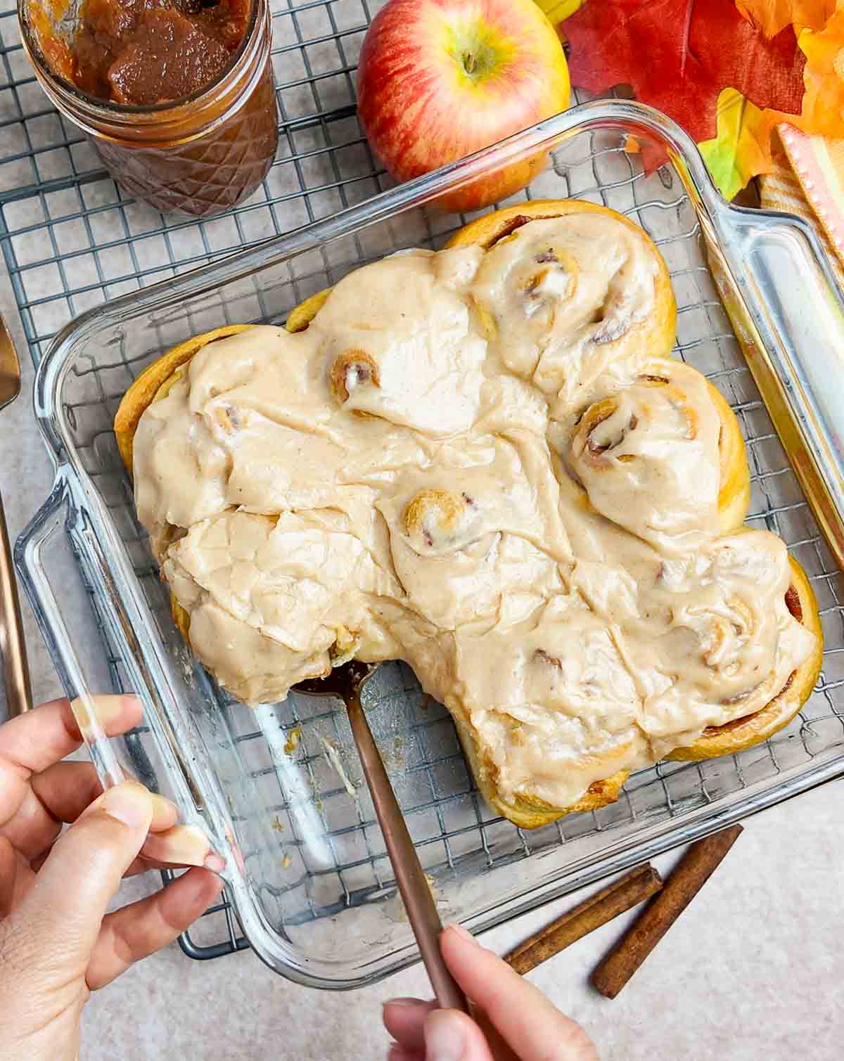 Taking out an apple butter cinnamon roll from a baking pan